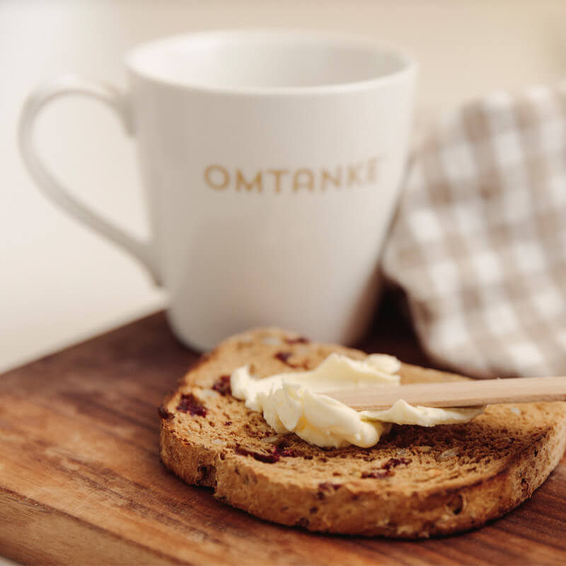 Fria kunskapsföretaget, en porslinsmugg och en rostad brödskiva som någon smörar